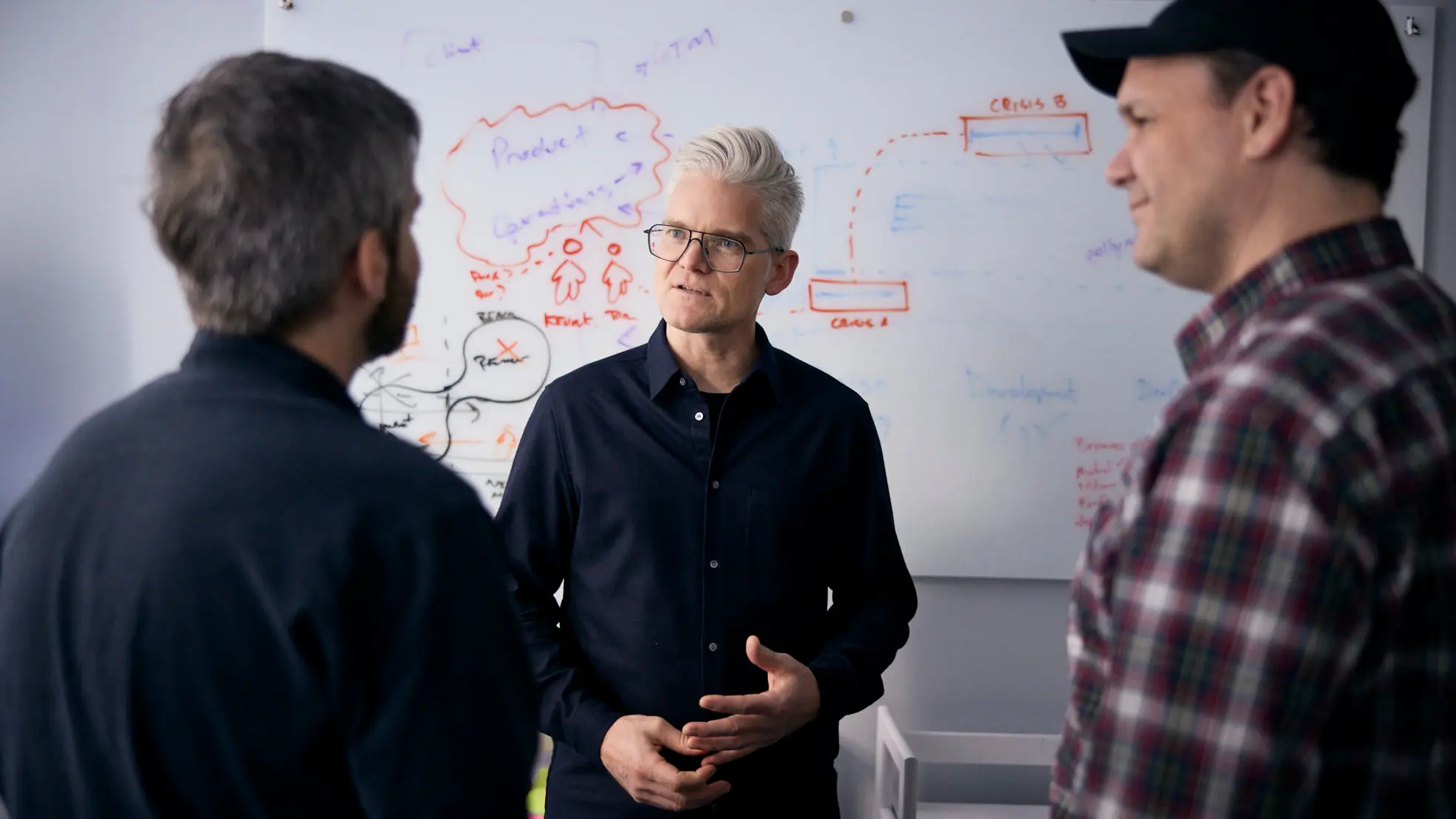 Three men collaborating in front of a whiteboard
