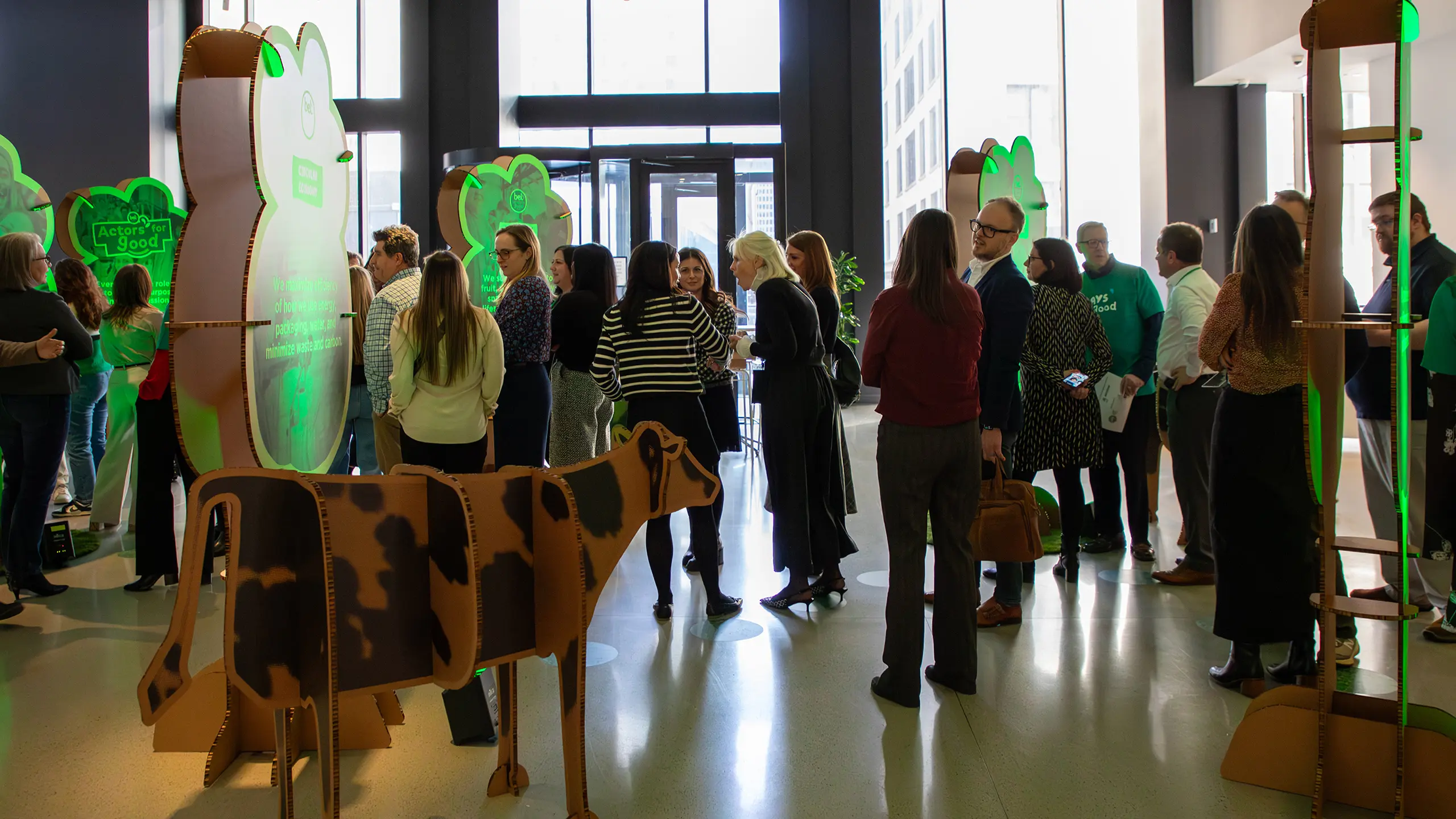 Lobby of the ‘All In 2025’ with experiential trees and cows and event goers