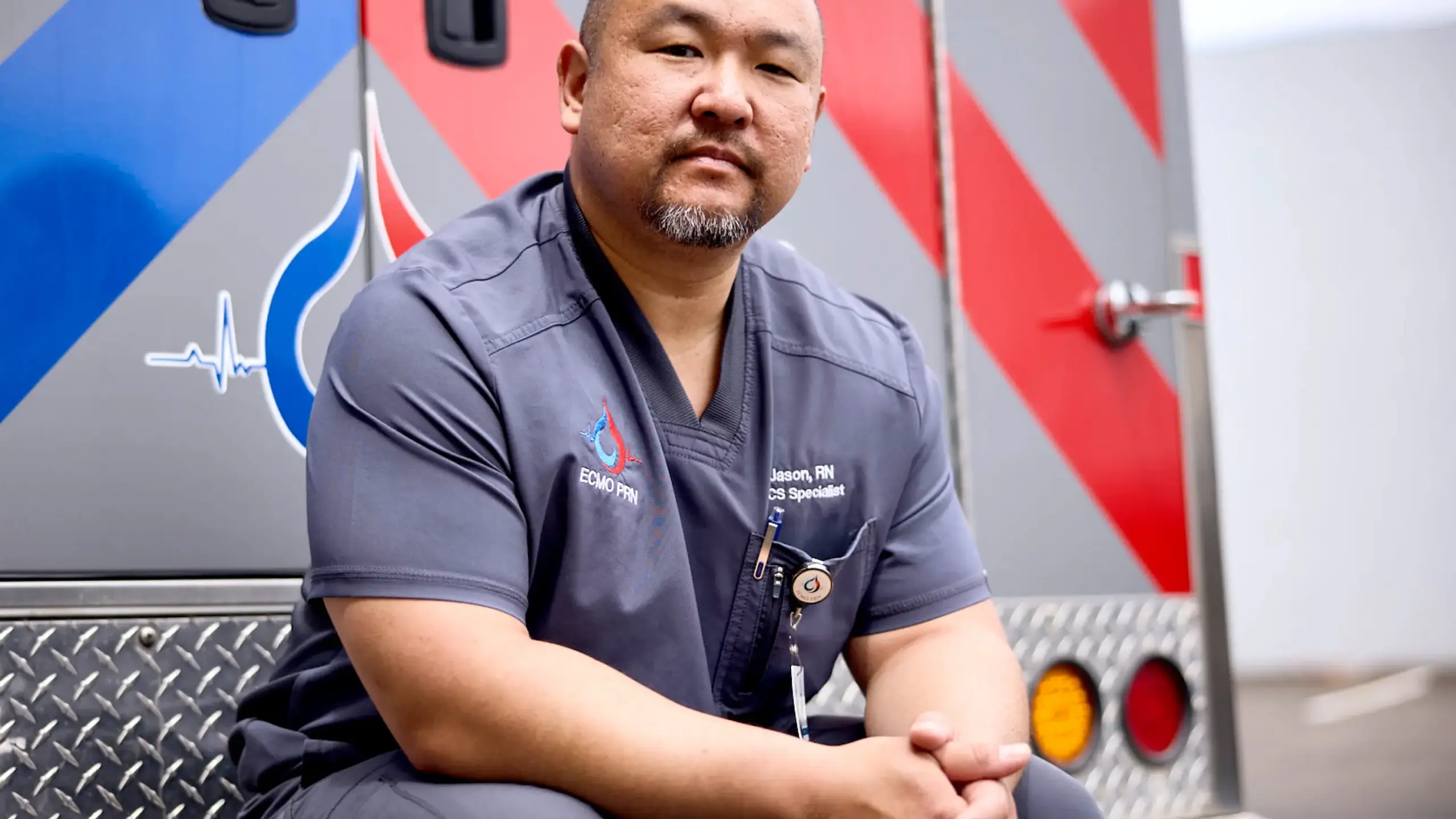 Paramedic and Ferno customer sitting on the back bumper of an ambulance
